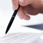 primo piano di una mano con una penna che firma un documento