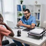 due persone alla scrivania di un ufficio uno di fronte all'altro uno